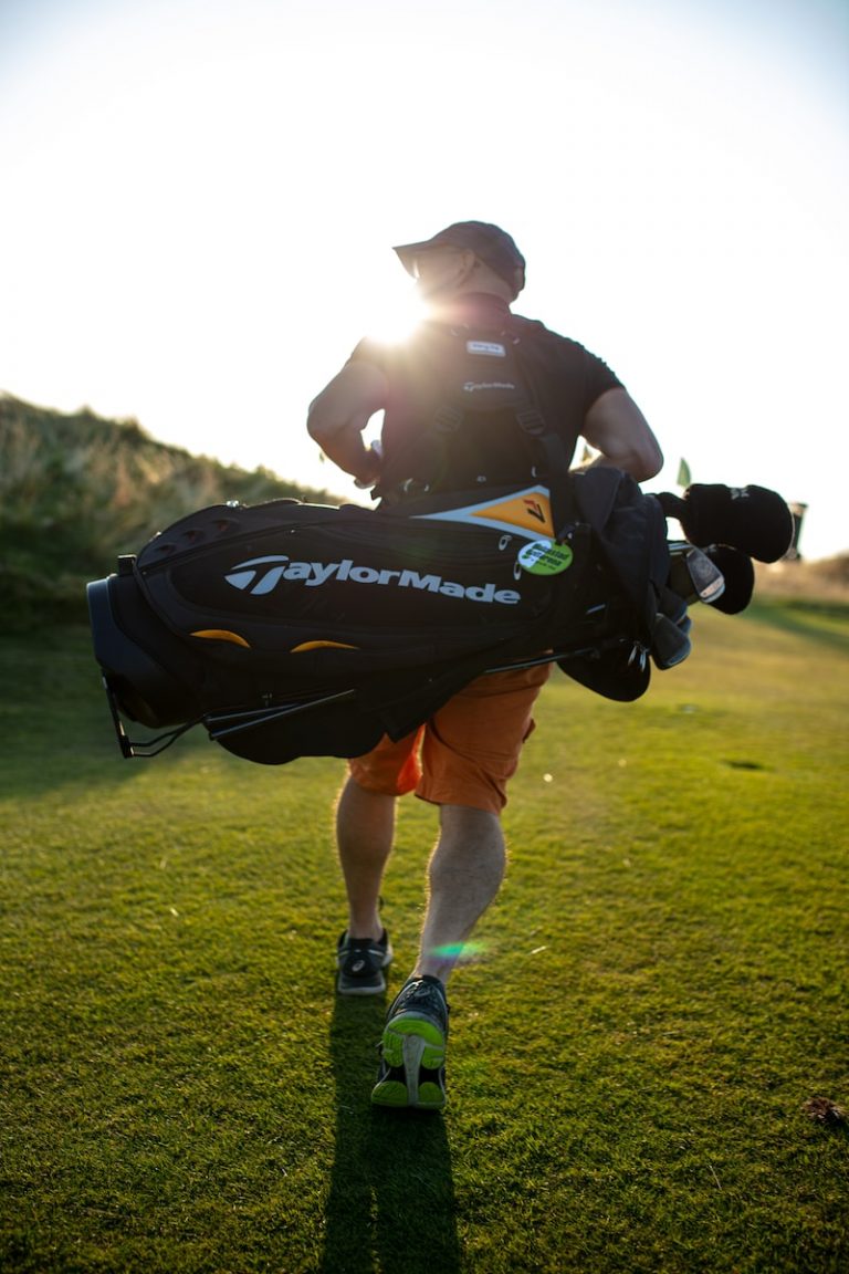 A man carrying a bag of golf equipment."